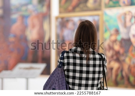 Cultural education. Back view of woman visiting excursion in museum. Defocused paintings in background. Concept of exhibition in gallery.