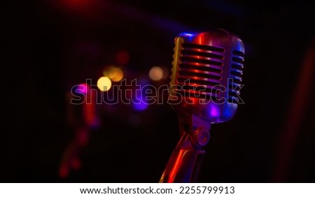 Professional microphone on black background with bokeh lights in rays of blue-red light, close-up. Web banner with copy space for design