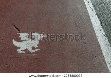 Funny pedestrian sidewalk in the medieval village of Gradara (Italy), with a middle age dragon shape over the white and red stripes on asphalt road