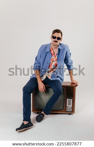 Back in time 90s 80s lifestyle concept. Studio footage of stylish cheerful young man in vintage retro jacket with antique old tv, candy-colored fashions, creativity, emotions, facial expression Royalty-Free Stock Photo #2255807877