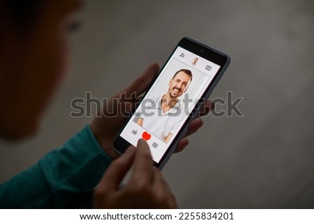 Woman giving like to photo on social media. Unrecognizable person swiping and liking profiles on online dating application to find love, partner and boyfriend selective focus, blurred background