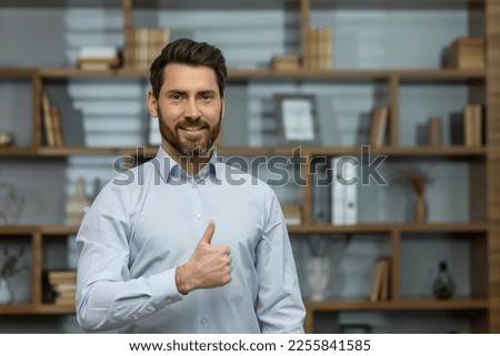 Close-up photo. Portrait of a young handsome successful man businessman, lawyer. Standing in a white shirt in the office, looking at the camera, pointing super, smiling.