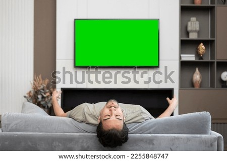 Man sitting on the couch and watching tv. Green screen concept	
