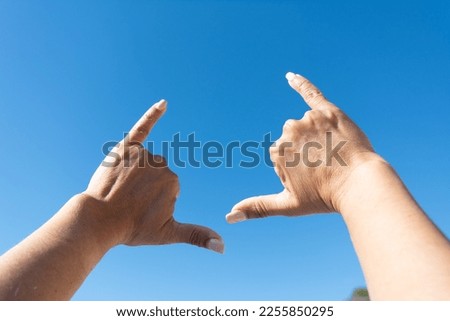 woman's hands showing surfer sign against blue sky background