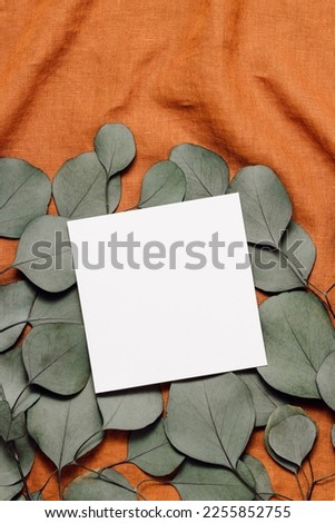 Aesthetic paper mockup card on eucalyptus leaves on linen brown cloth. Paper card with copy space for logo, invitation and wedding, minimal blog and business template, bohemian concept