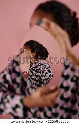 Graphic portrait of unrecognizable black woman holding mirror with optical illusion, self reflection concept Royalty-Free Stock Photo #2255853885