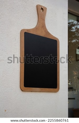 Vertical photo. Wooden cutting board on white wall of restaurant with glass door. Black chalk board. Mock up space. Place for text. Offer. Street cafe menu. Catering concept. Copyspace. Public. Pub