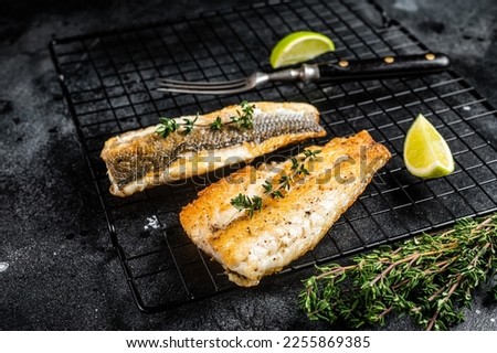Grilled sea bass fillet with lime and thyme. Black background. Top view. Royalty-Free Stock Photo #2255869385