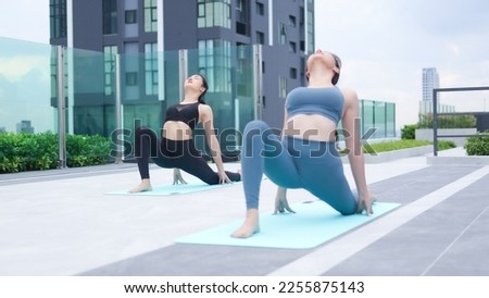 Asian woman doing yoga or Pilates exercise outdoors on the roof of building