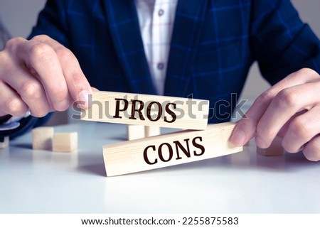 Close up on businessman holding a wooden block with "Pros or Cons?" message Royalty-Free Stock Photo #2255875583