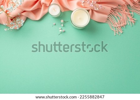 Hello spring concept. Top view photo of candles in glass holders gypsophila flowers and pink scarf on isolated teal background with empty space