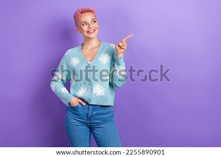 Portrait of positive toothy beaming girl pink hairdo wear blue pullover directing look empty space isolated on violet color background