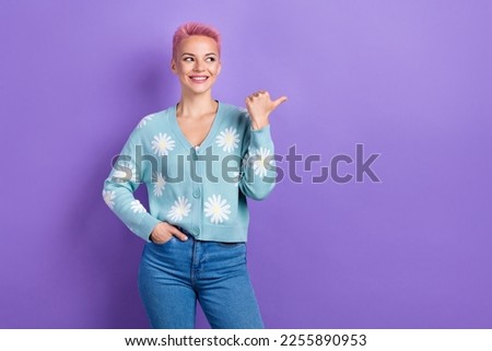 Portrait of toothy beaming nice girl with pink hairdo wear blue pullover directing look empty space isolated on violet color background