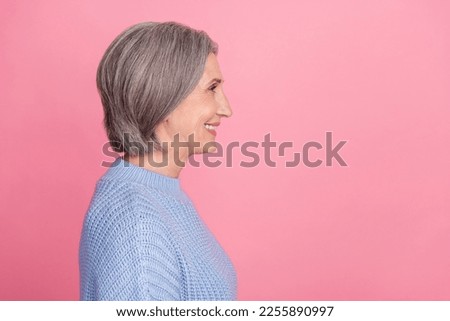 Side profile photo of mature aged old senior cheerful grandmother woman gray hair smiling looking empty space ad isolated on pink color background