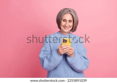 Closeup photo portrait of grey hair old woman wear blue knit pullover hold her modern device phone chat with son isolated on pink color background