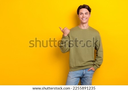 Photo of cheerful satisfied man beaming smile look indicate finger empty space isolated on yellow color background