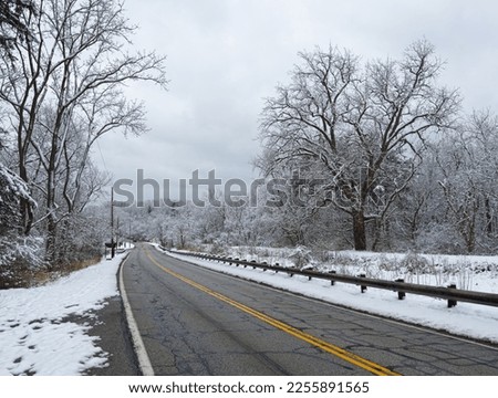 A road in Ohio's Cuyahoga Valley near Cleveland runs through a wintry landscape after freshly fallen snow Royalty-Free Stock Photo #2255891565