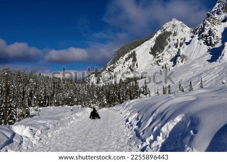 View of Visoka Pec mountain and landscape bellow in Tamar valley in Gorenjska, Slovenia with people sledding