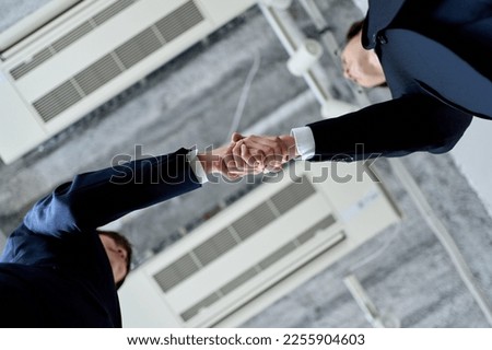 Male and female Asian business people shaking hands Royalty-Free Stock Photo #2255904603