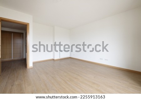 Empty room with wooden floor, aluminum radiator, and built-in wardrobe with wooden doors