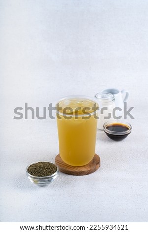 Iced oolong green tea in plastic cup on white rustic background