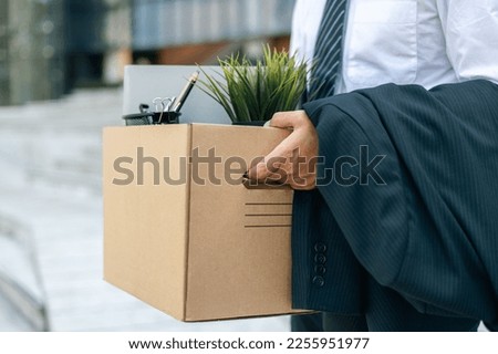 Businessman with box cardboard packing personal items after losing jobs. Failure businessman standing at front of building. Your fired Unemployed Jobless People Crisis Royalty-Free Stock Photo #2255951977