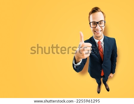 Full body businessman in eye glasses, black suit show thumb up like, agree hand sign gesture, yellow background. Comic cartoon style funny man in eyeglasses, big head. Funny face. Expert recommending