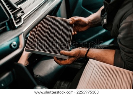 Cropped picture of a mechanic changing old and dirty air filter in car.