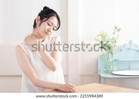 Asian woman with stiff shoulders Royalty-Free Stock Photo #2255984389