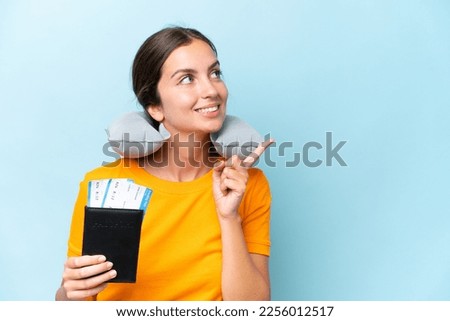 Young beautiful woman with Inflatable travel Pillow isolated on blue background intending to realizes the solution while lifting a finger up