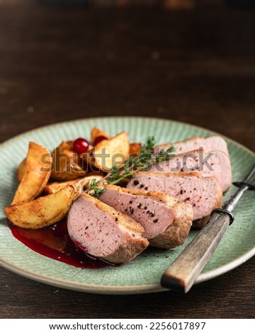 Roast duck breast with potatoes and berry sauce, selective focus, place for text