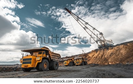Large quarry dump truck. Big yellow mining truck at work site. Loading coal into body truck. Production useful minerals. Mining truck mining machinery to transport coal from open-pit production Royalty-Free Stock Photo #2256020737