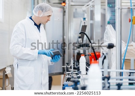 Engineer operator inspecting milk bottles production line dairy factory industry, automatic conveyor for transporting. Royalty-Free Stock Photo #2256025113
