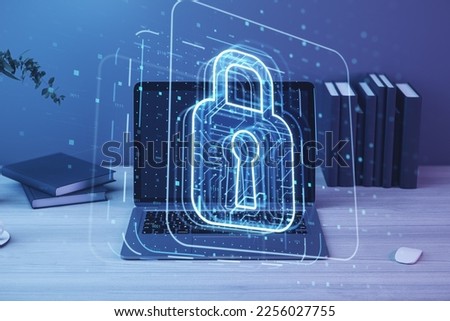 Close up of laptop on desktop with books and glowing padlock hologram on blurry background. Secure, safety and web protect concept. Double exposure