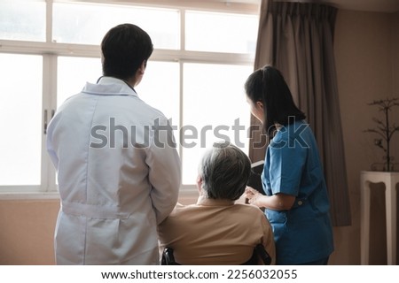 Group of young medical professionals as male and female doctor and nurse in uniform and lab coat helping senior old man walk in hospital room during treatment and therapy session for recovery