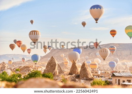 Landscape of fabulous Kapadokya. Colorful flying air balloons in sky at sunrise in Anatolia. Vacations in beautiful destination in Goreme, Turkey  Royalty-Free Stock Photo #2256042491