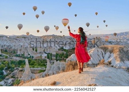 Bogo girl traveler vacations beautiful destination in Goreme, Turkey. Fabulous Kapadokya with flying air balloons at sunrise, Anatolia Royalty-Free Stock Photo #2256042527