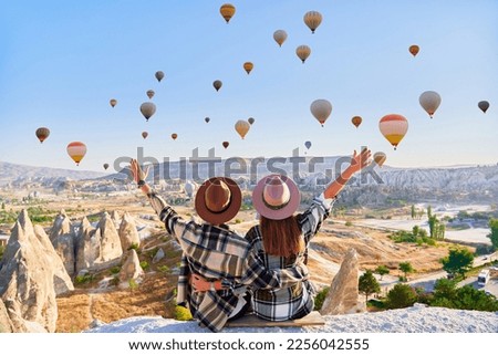Couple travelers vacations together in beautiful destination in Goreme, Turkey. Fabulous Kapadokya with flying air balloons at sunrise, Anatolia Royalty-Free Stock Photo #2256042555