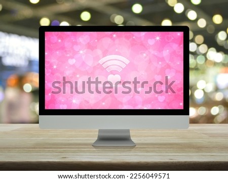 Heart love wifi flat icon on desktop modern computer monitor screen on wooden table over blur light and shadow of shopping mall, Internet online love connection, Valentines day concept