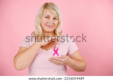 Happy Woman show pink ribbon, great for prevention breast cancer concept. Everything pink, the background, the ribbon and the shirt. High quality photo