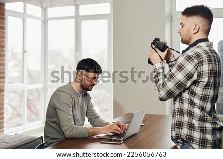 A photographer takes a picture of a man with a laptop. Concept photo for business, programmers.