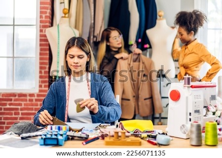 Portrait of young beautiful woman fashion designer stylish sitting and working with color samples.Attractive young girl working with colorful fabrics at fashion studio