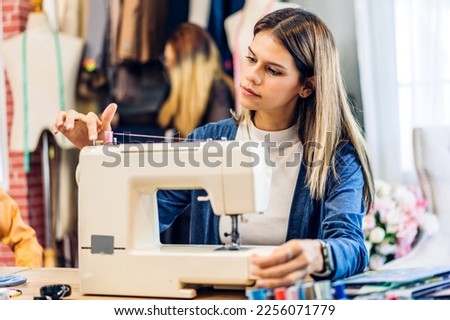 Portrait of young beautiful woman fashion designer stylish sitting and working with color samples.Attractive young girl working with colorful fabrics at fashion studio