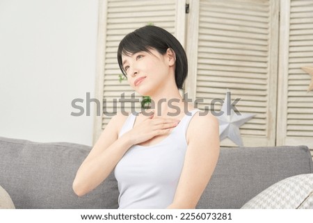 Asian woman massage the chest at home Royalty-Free Stock Photo #2256073281