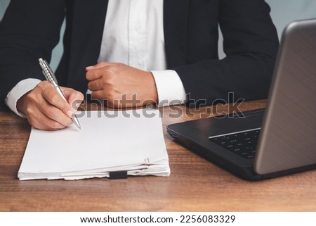 Signature concept. A businessman in a suit signing a lease contract or agreement while sitting at the table in the office. Close-up photo. Business and documents management concept