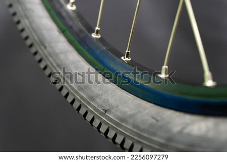 Bicycle tire and wheel close-up on a black background. Abstract background of a wheel in a bicycle workshop. Dirty old worn-out tire. Royalty-Free Stock Photo #2256097279