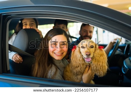 Attractive latin mom with her family and kids in the car traveling with a beautiful golden cocker spaniel dog Royalty-Free Stock Photo #2256107177