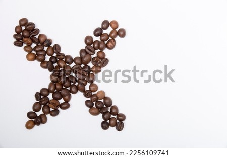 X is a capital letter of the English alphabet made up of natural roasted coffee beans that lie on a white background. Plenty of space to put text or pictures, top view and studio photography.