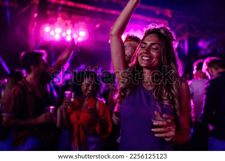 A young Caucasian woman is dancing at a concert having a good time at an open air venue in the night. Royalty-Free Stock Photo #2256125123