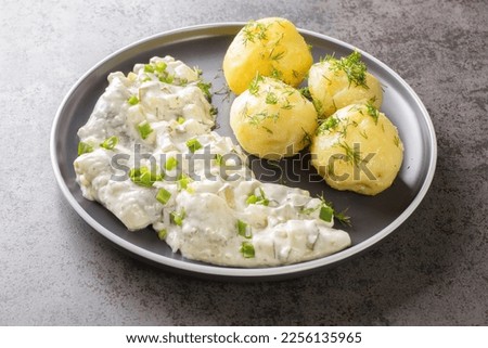 Herring fillet with apples, pickles, onions in a creamy sauce with a side dish of boiled potatoes close-up in a plate on the table. horizontal
 Royalty-Free Stock Photo #2256135965